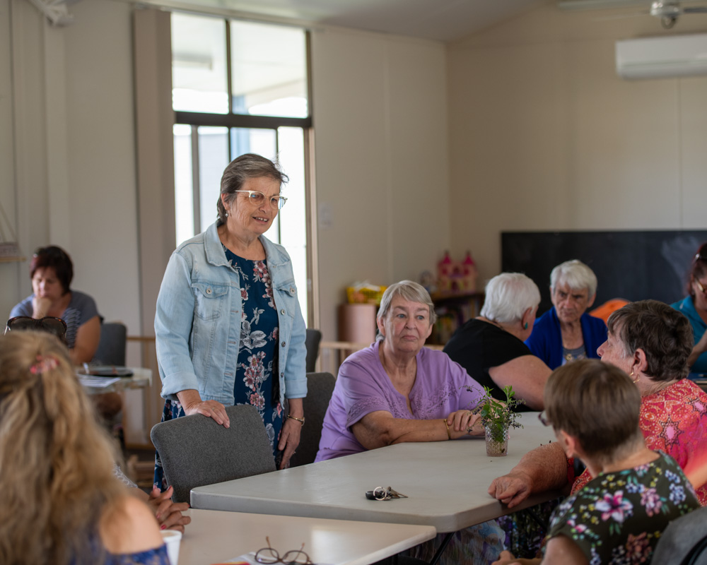 Room of older women with one standing behind chair