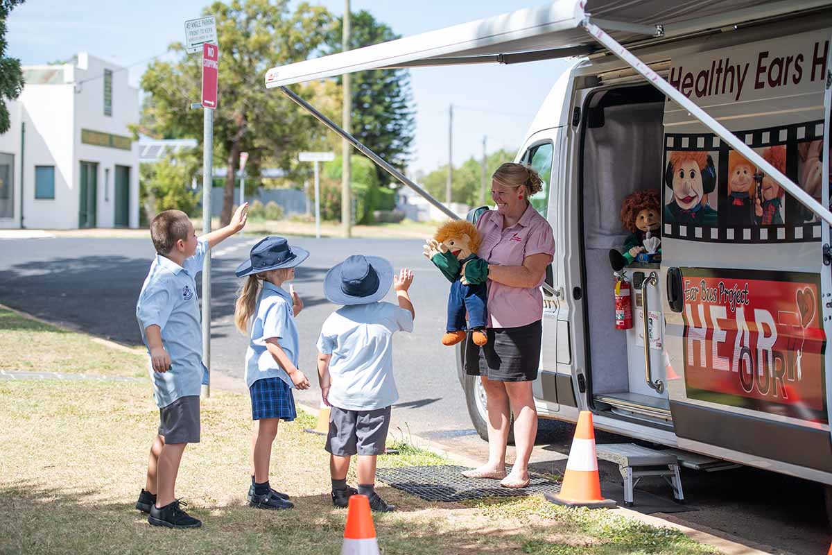 Kids and a woman outside the 'Healthy Ears Bus'